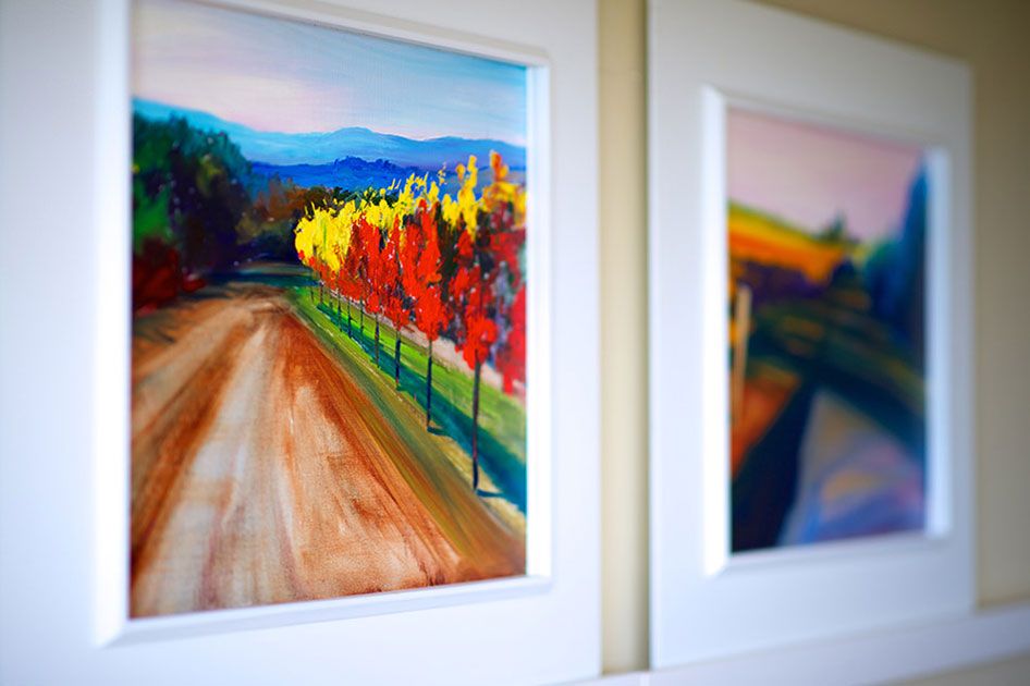 Two framed landscape paintings by the artist Ann Rea on a wall