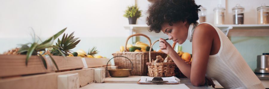aspiring female entrepreneur working on a business idea in her home office. Considering what skills and traits she needs to work on to find success.